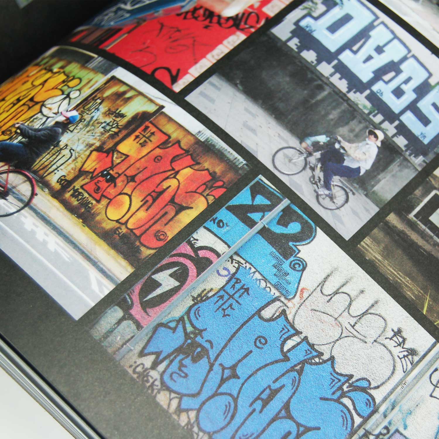 Open book from 'Graffiti Asia' showing a page with multiple photos of graffiti. The images include colorful graffiti art on walls, a person riding a bicycle in front of a large graffiti piece, and various graffiti tags and designs.